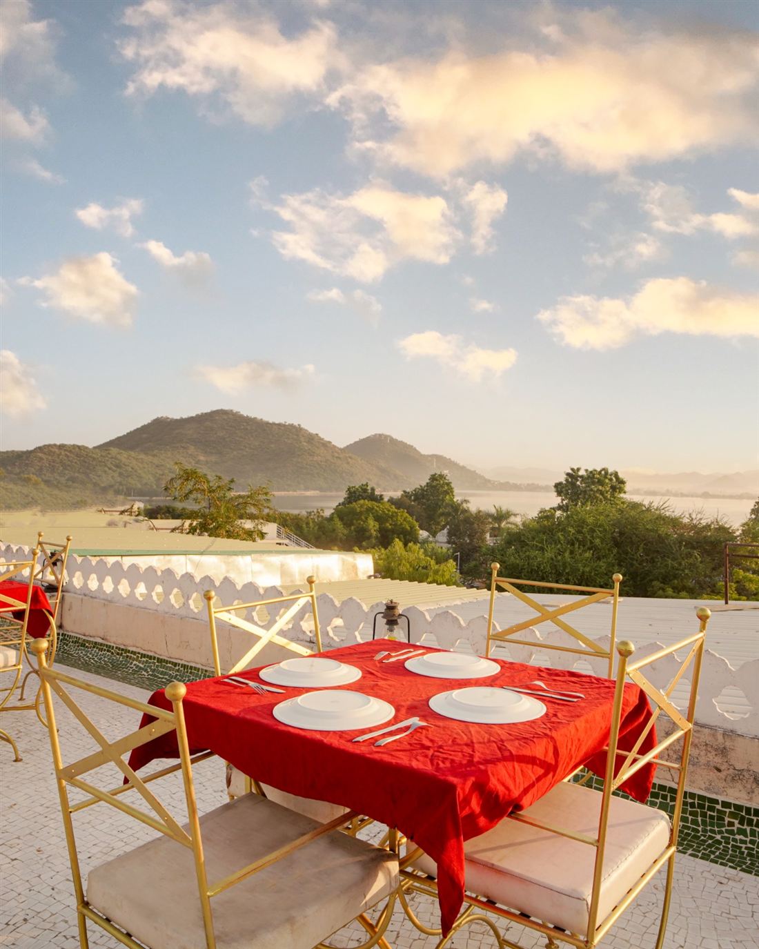 Terrace tables at dusk with the lit Aravalli hillside behind