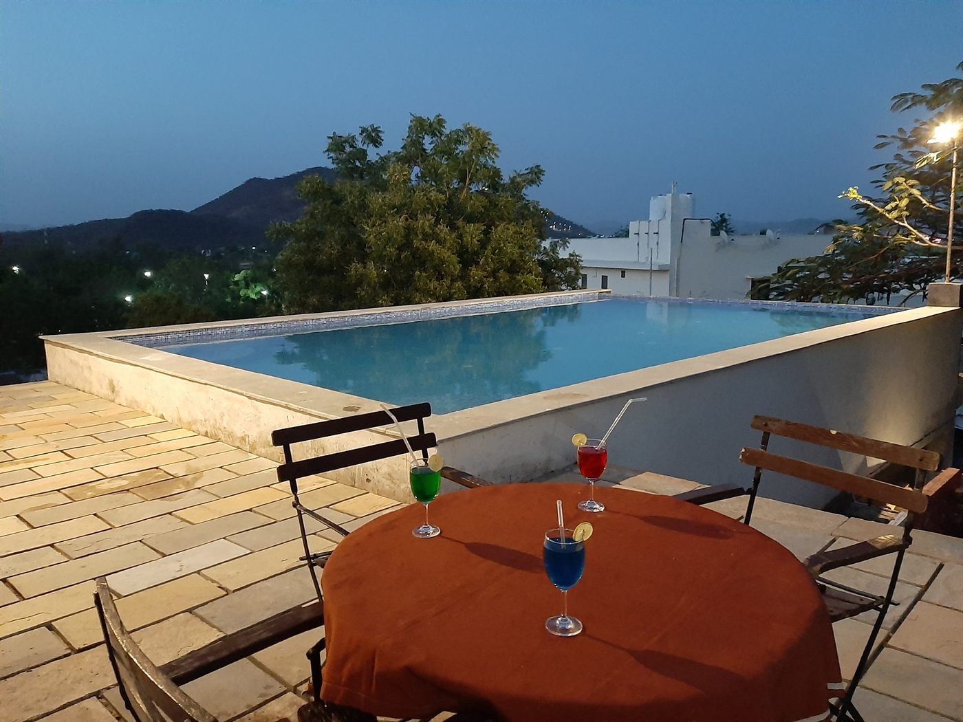 Infinity pool at Vikram Garh Lakeview at dusk, its edge looking out over the Aravalli hills, Udaipur